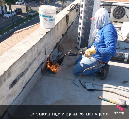אדם משתמש במבער לאיטום גג עם יריעות ביטומניות.